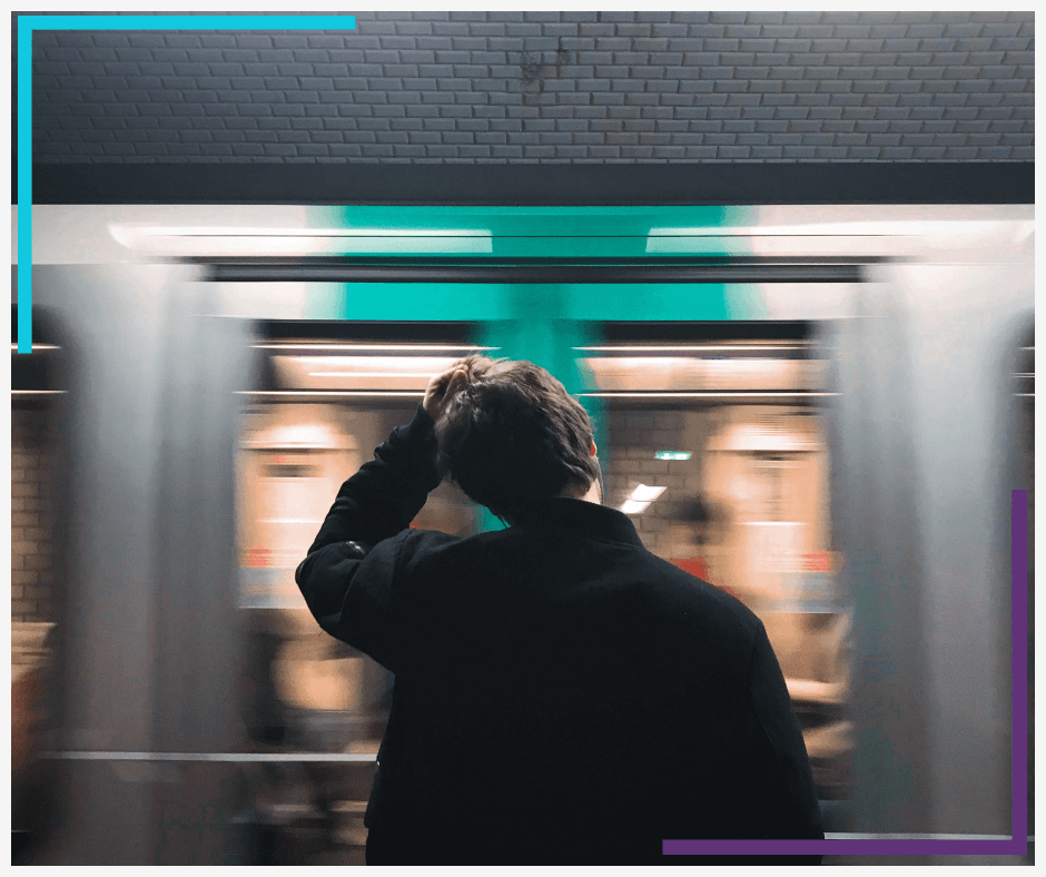 A man stands with his hand on his head watching a subway go by.
