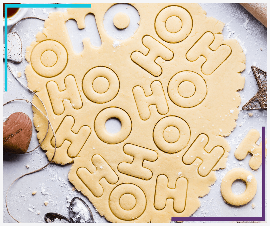 Sugar cookie dough sits on a table partially cut by H and O cookie cutters so it says HOHOHO