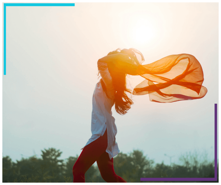 A woman holds a scarf up and allows it to be lifted by the wind.